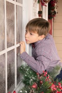Boy Looking Into Window With Artificial Snow